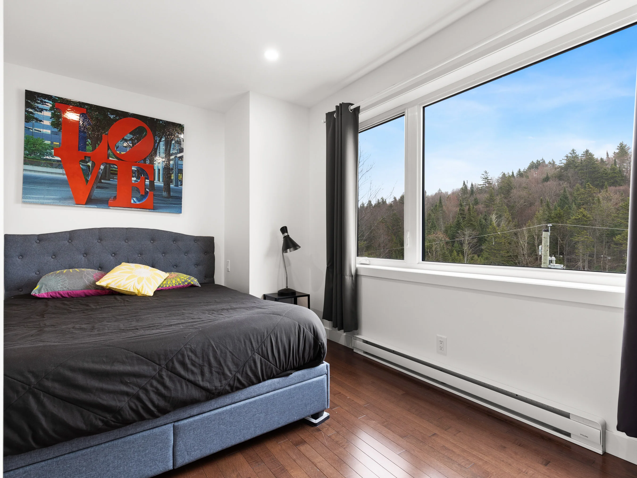 Chambre avec lit queen, grande fenêtre et vue sur la forêt du chalet Le Céleste